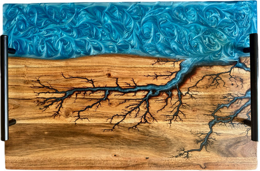 Australian handmade charcuterie board with sky blue resin river flowing through fractal burned acacia timber, fitted with black handles, Fractal Flow Designs