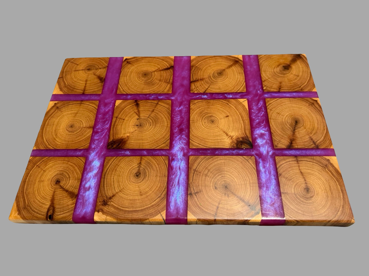 A rectangular wooden board with a grid pattern of circular wood slice designs and three vertical purple glittery stripes, shown on a solid gray background.