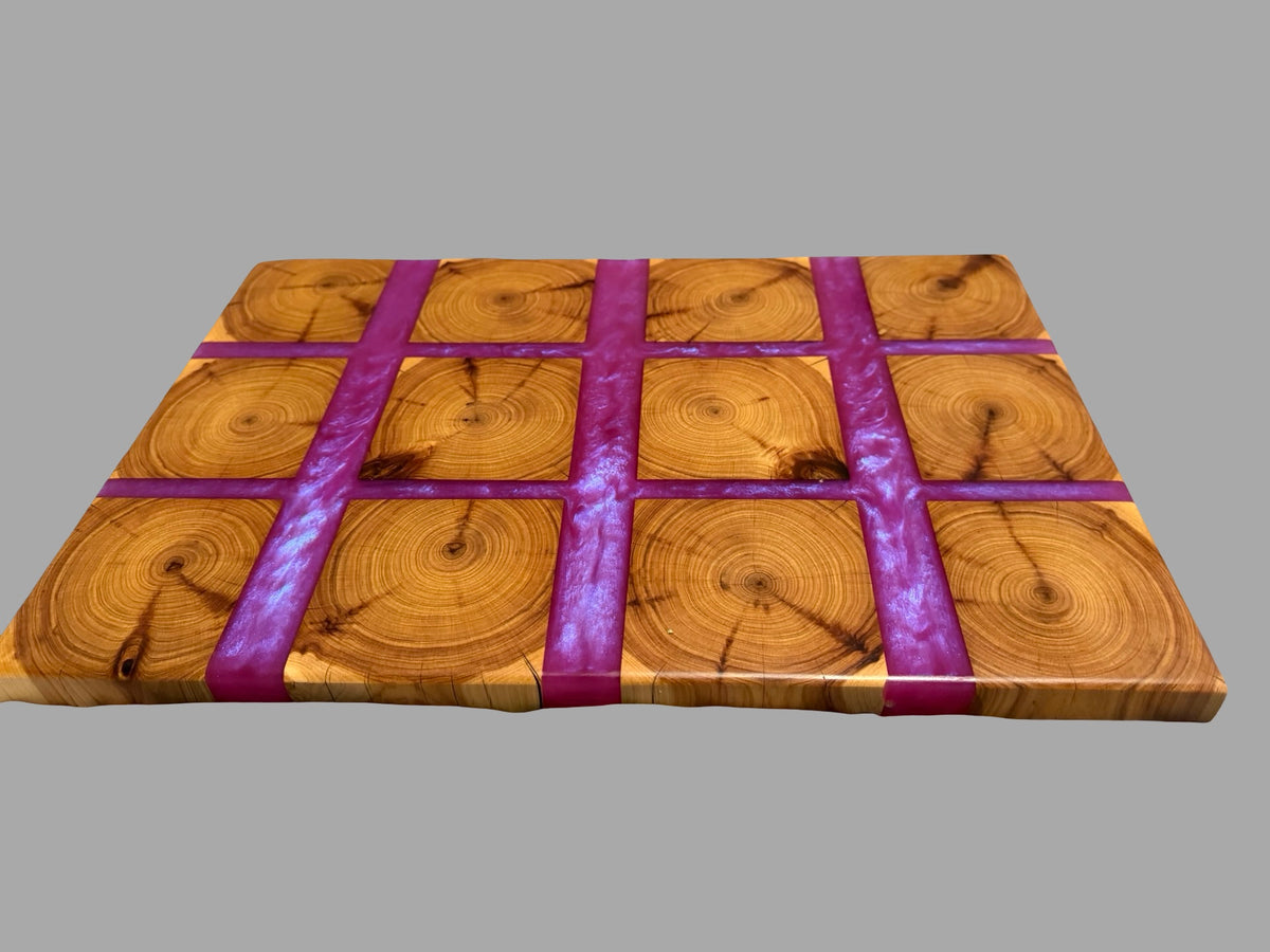 A square wooden board with a grid pattern of circular wood slices, bound by four thick purple ribbons, shown on a solid gray background.