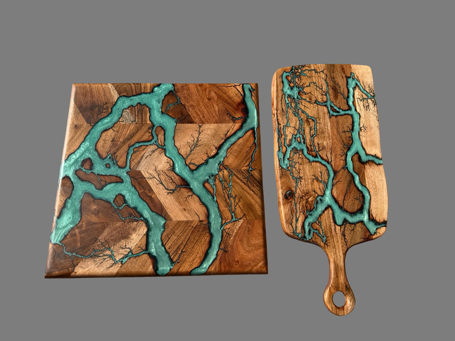 Two resin boards with a natural wood grain pattern and teal resin inlay, shown on a solid gray background. , made in Australia