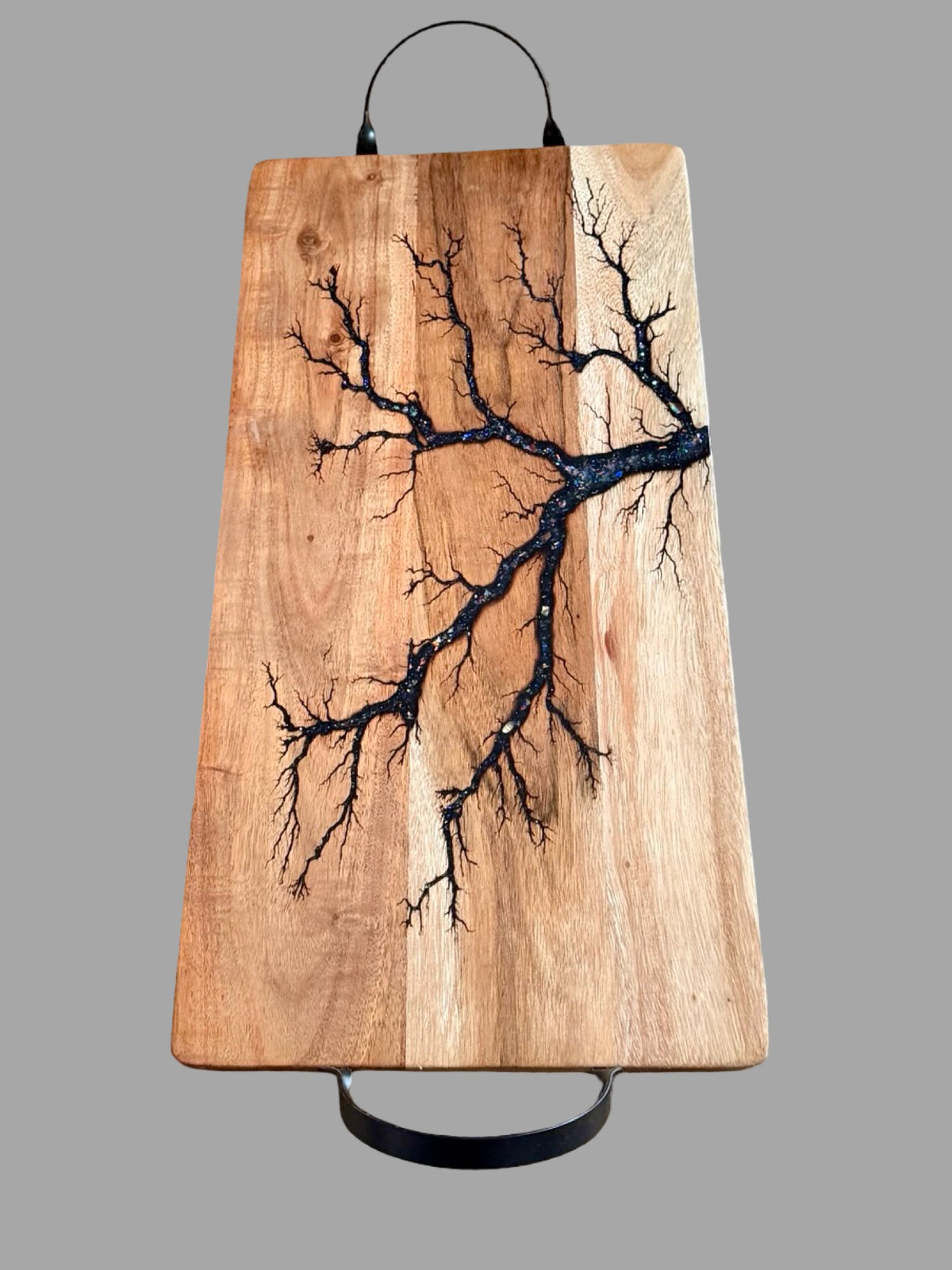 One of a kind 500 x 250 x 12mm acacia serving board with black metal handles, glittering blue resin artwork and handcrafted fractal burning for stylish entertaining