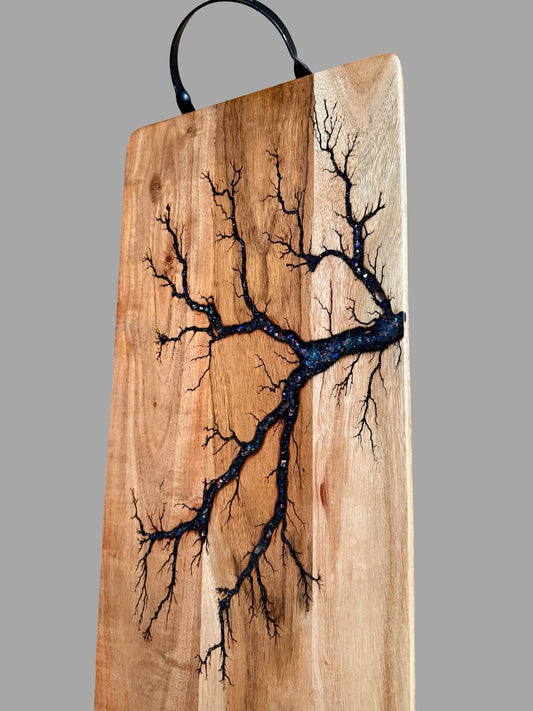 Handmade 500 x 250mm acacia serving board featuring black metal handles, shimmering blue sparkle resin and unique fractal burn artwork for entertaining
